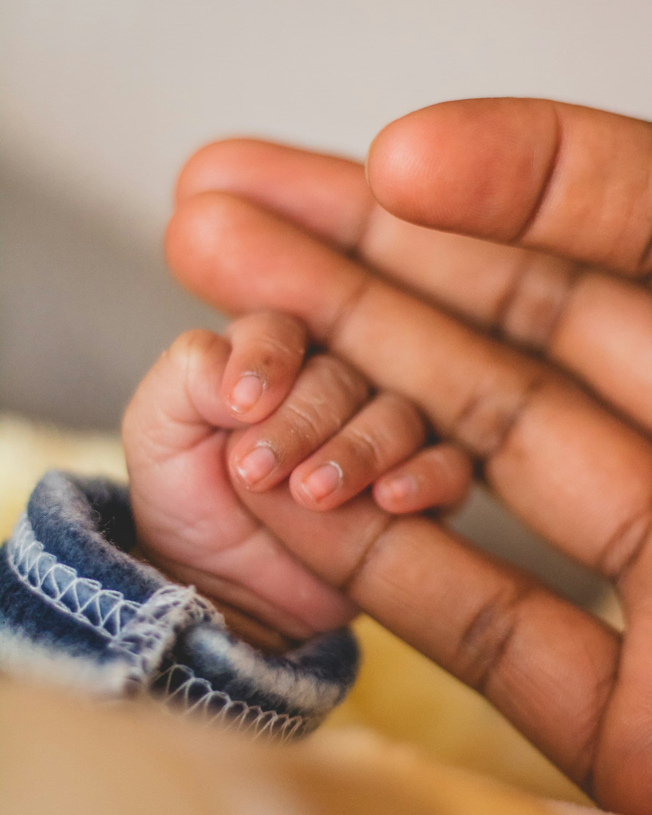 A baby’s hand gripping a parent’s finger