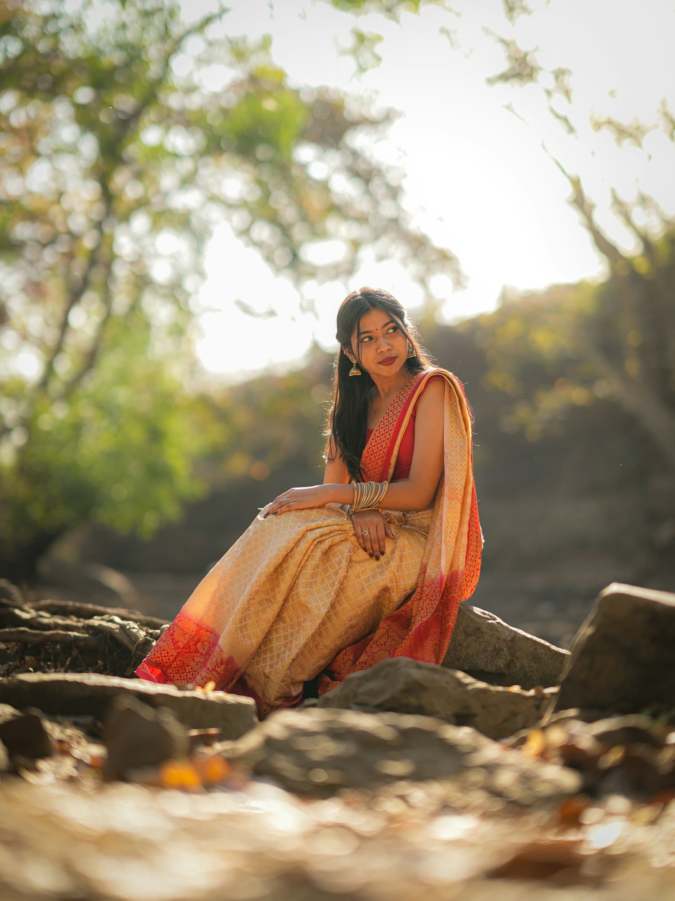 A woman in a sari sitting outdoors in warm light